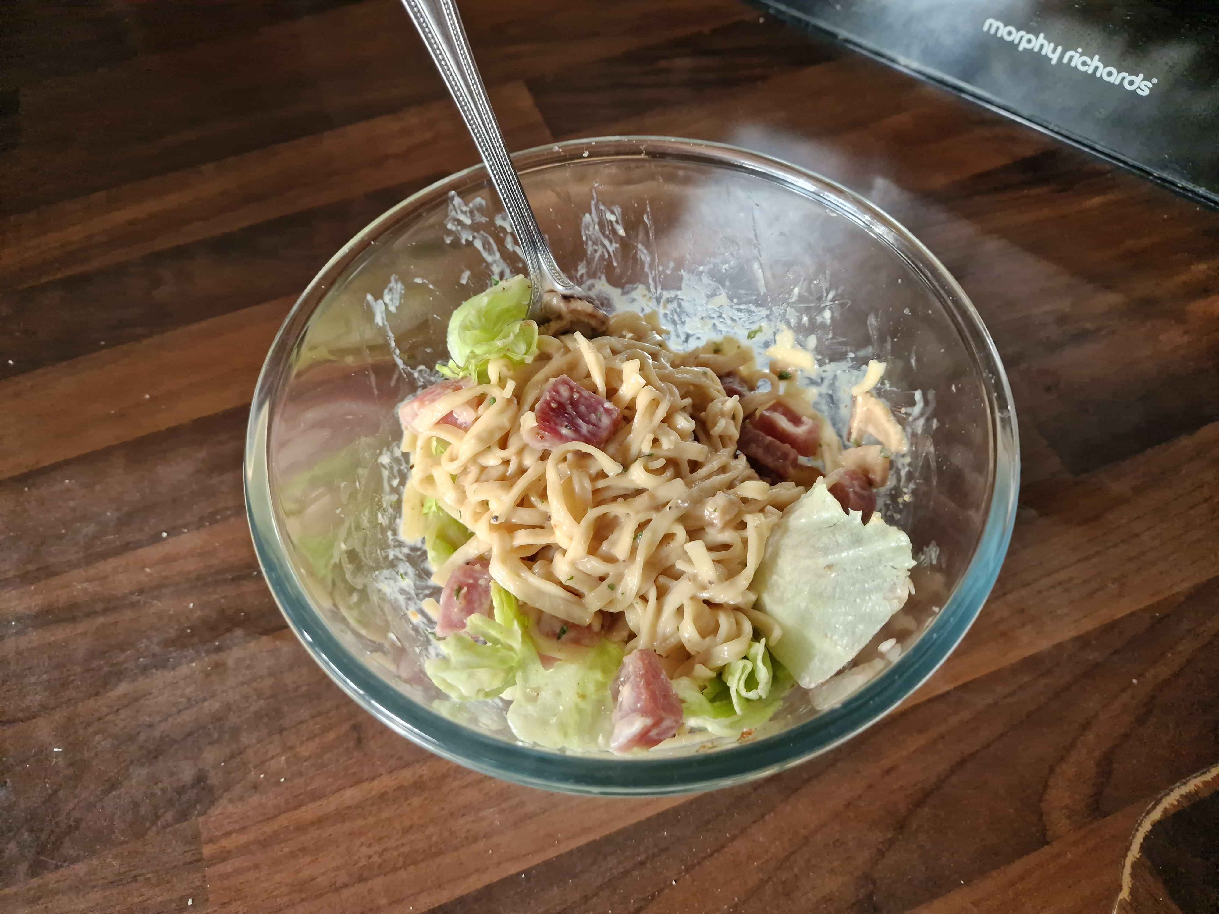 The prepared bowl of creamy mushroom noodles, accompanied by diced bits of prosciutto and lettuce.