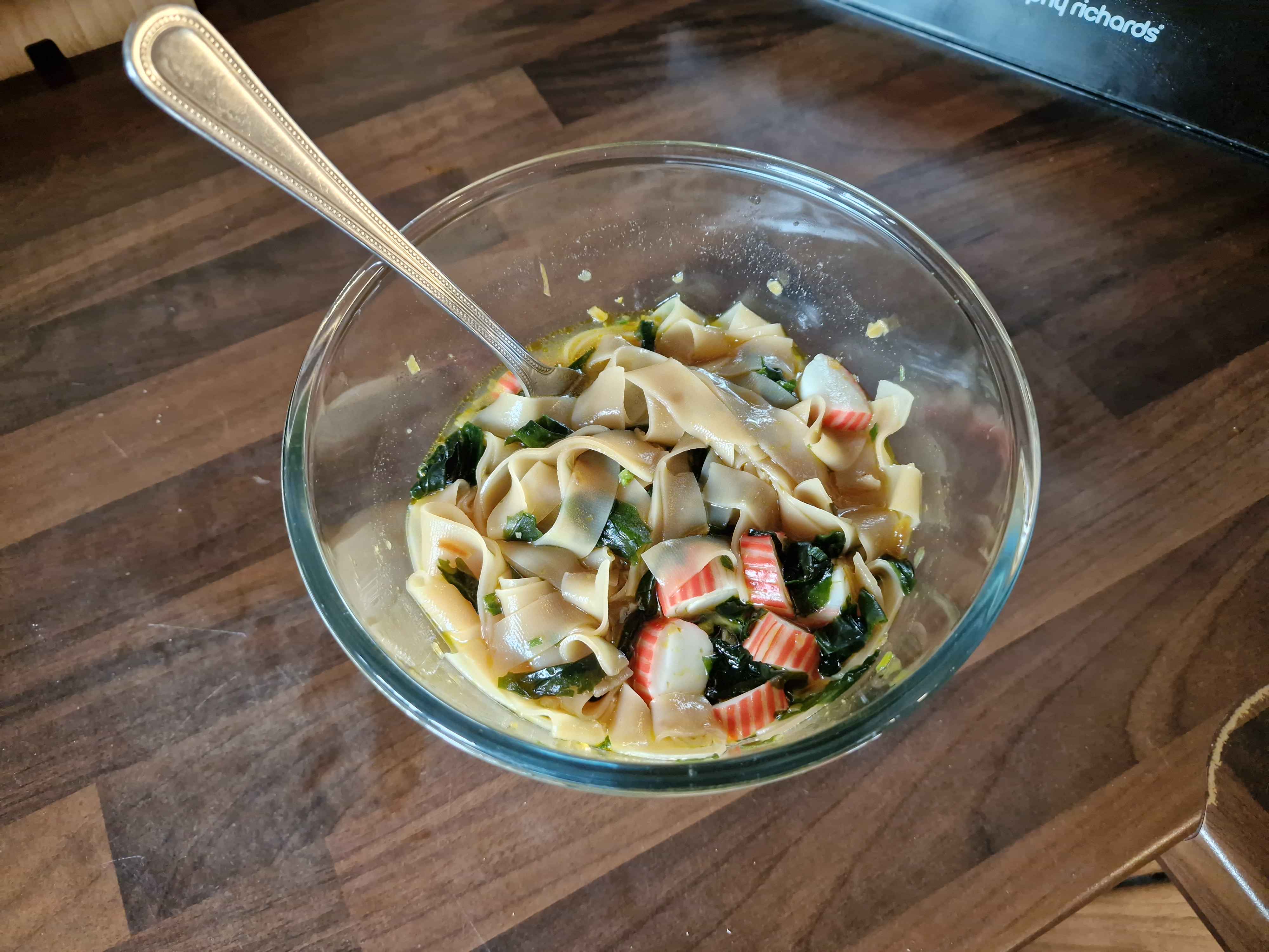 The completed bowl of noodles, with chopped imitation crab and seaweed.